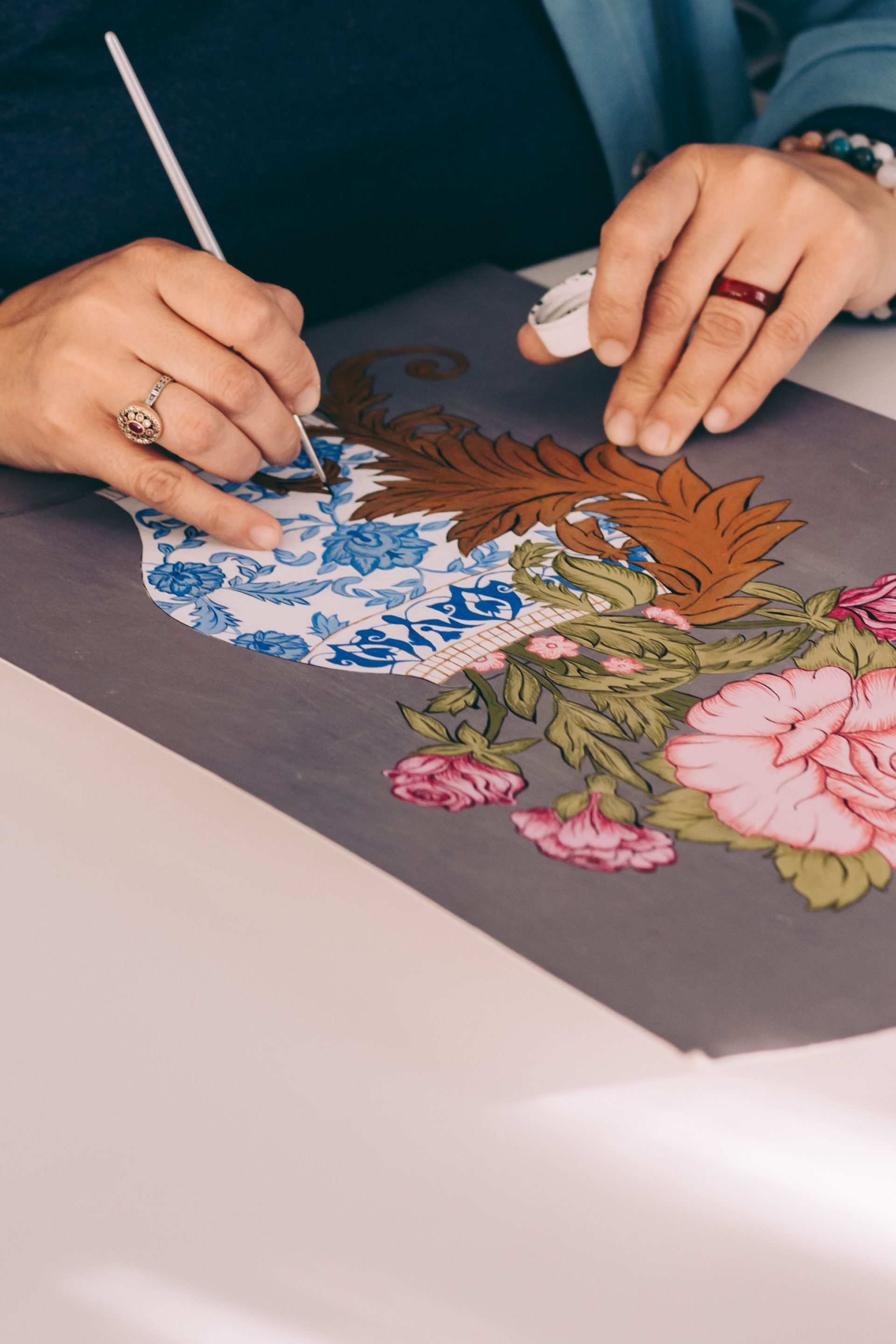A person painting intricate floral designs on a canvas, showcasing art creativity.